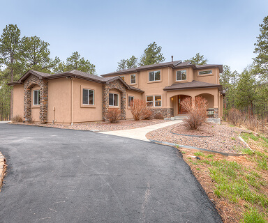 Spacious stucco and stone luxury home with curved driveway nestled among pine trees in Colorado Springs | Logo Inc Real Estate